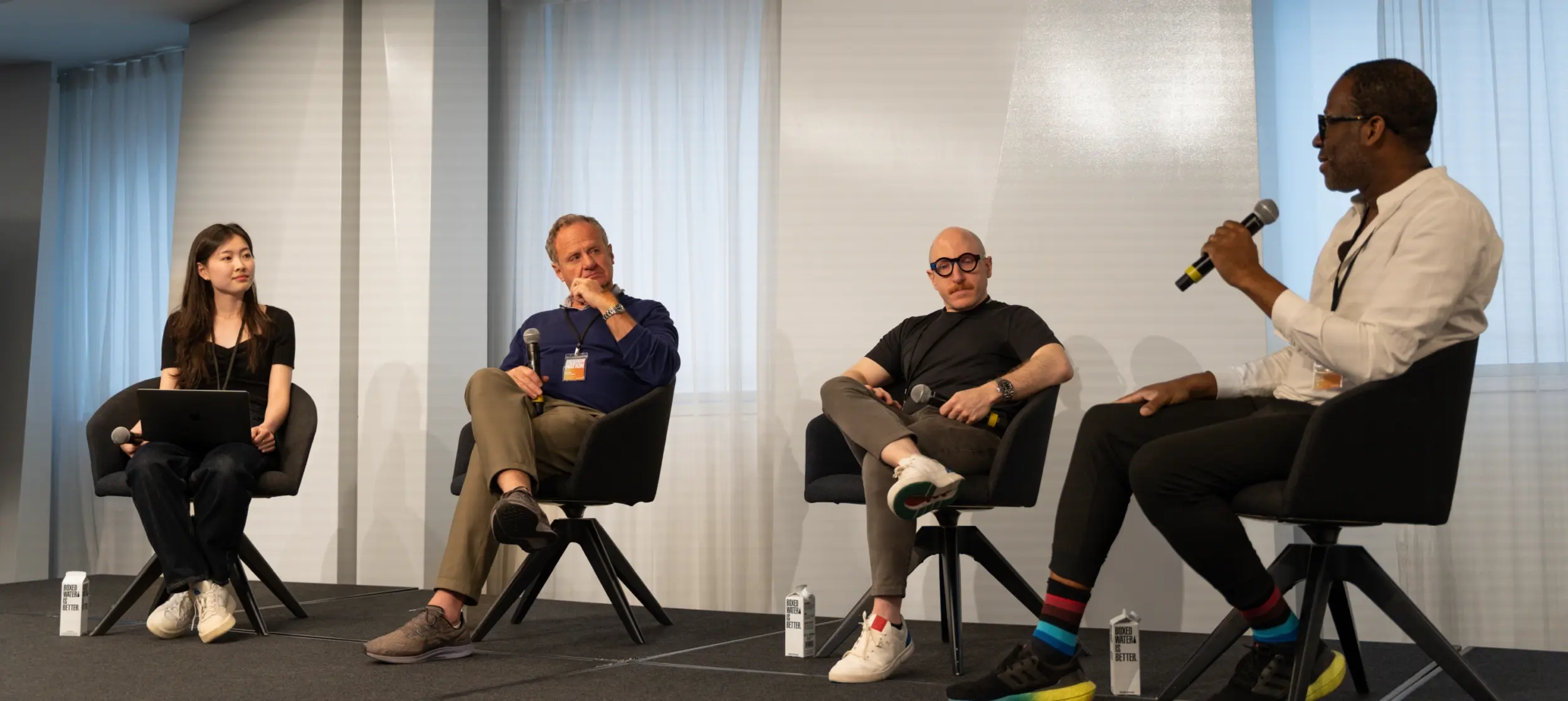 Four speakers, including Jacob Benbunan, seated on stage in chairs, engaging in a discussion at the Design Nation conference.